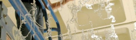 Gerri Sayler working on lift to install hot glue exhibit titled Numinous at Spurgeon Art Gallery