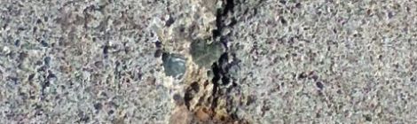 image of sidewalk crack wrapped around a circular metal object